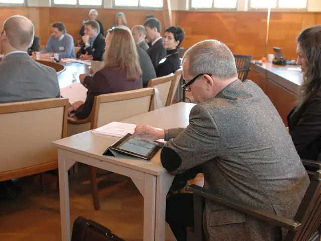 Here we have 2 people who are sitting on black chairs and this man is having tablet and lady is...
