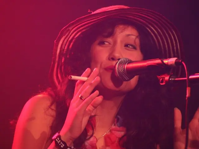 In this picture I can see a woman singing in the microphone and also she is holding a cigarette.