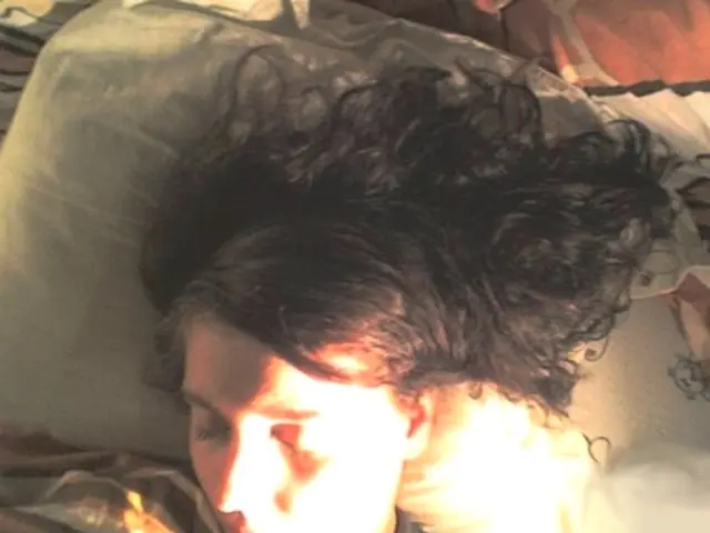 In this image I can see a person is sleeping. Under the head there is a pillow which is in white...