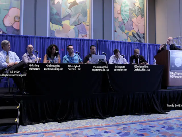 In this image there are a few people sitting on the chairs on the dais. In front of them there is a...